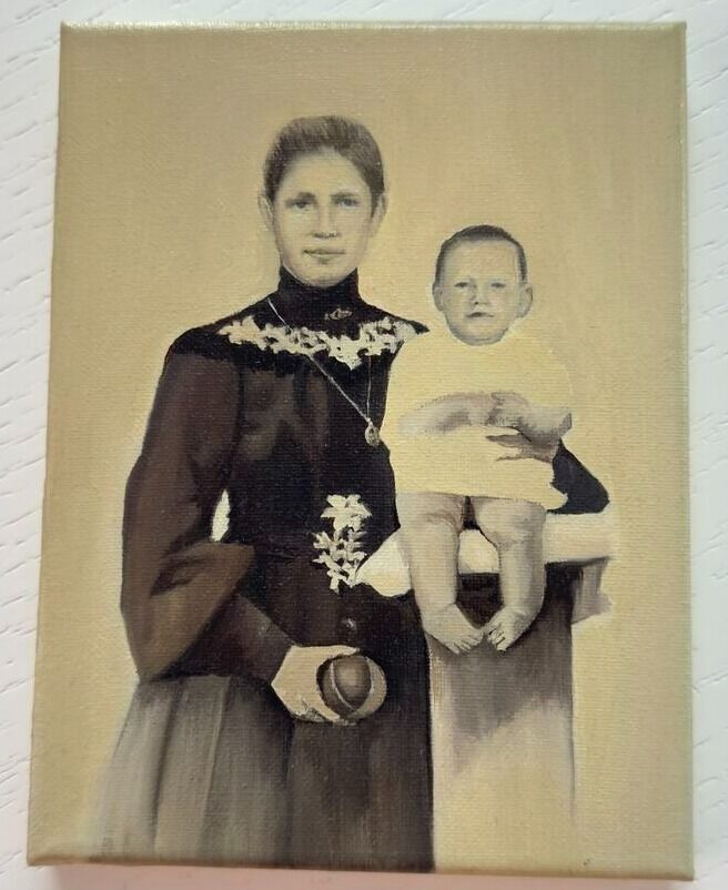 Старая раскрашенная фотография: женщина в тёмном платье со светлой кружевной отделкой стоит рядом с ребёнком в белом, сидящим на высокой подставке.