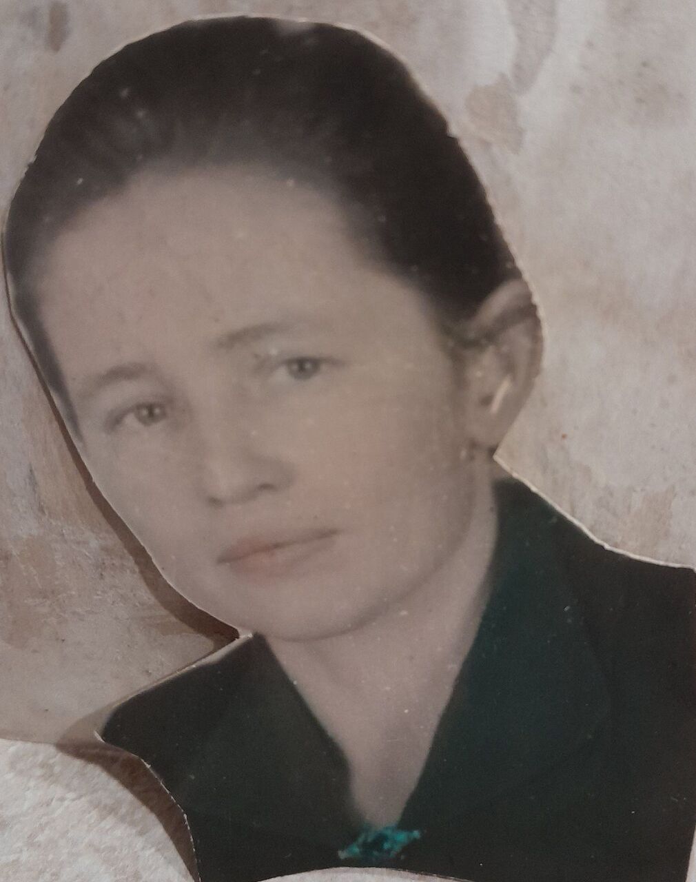 Раскрашенная старая фотография: молодая женщина с гладко зачёсанными тёмными волосами, в тёмной одежде; край снимка обрезан неровно.