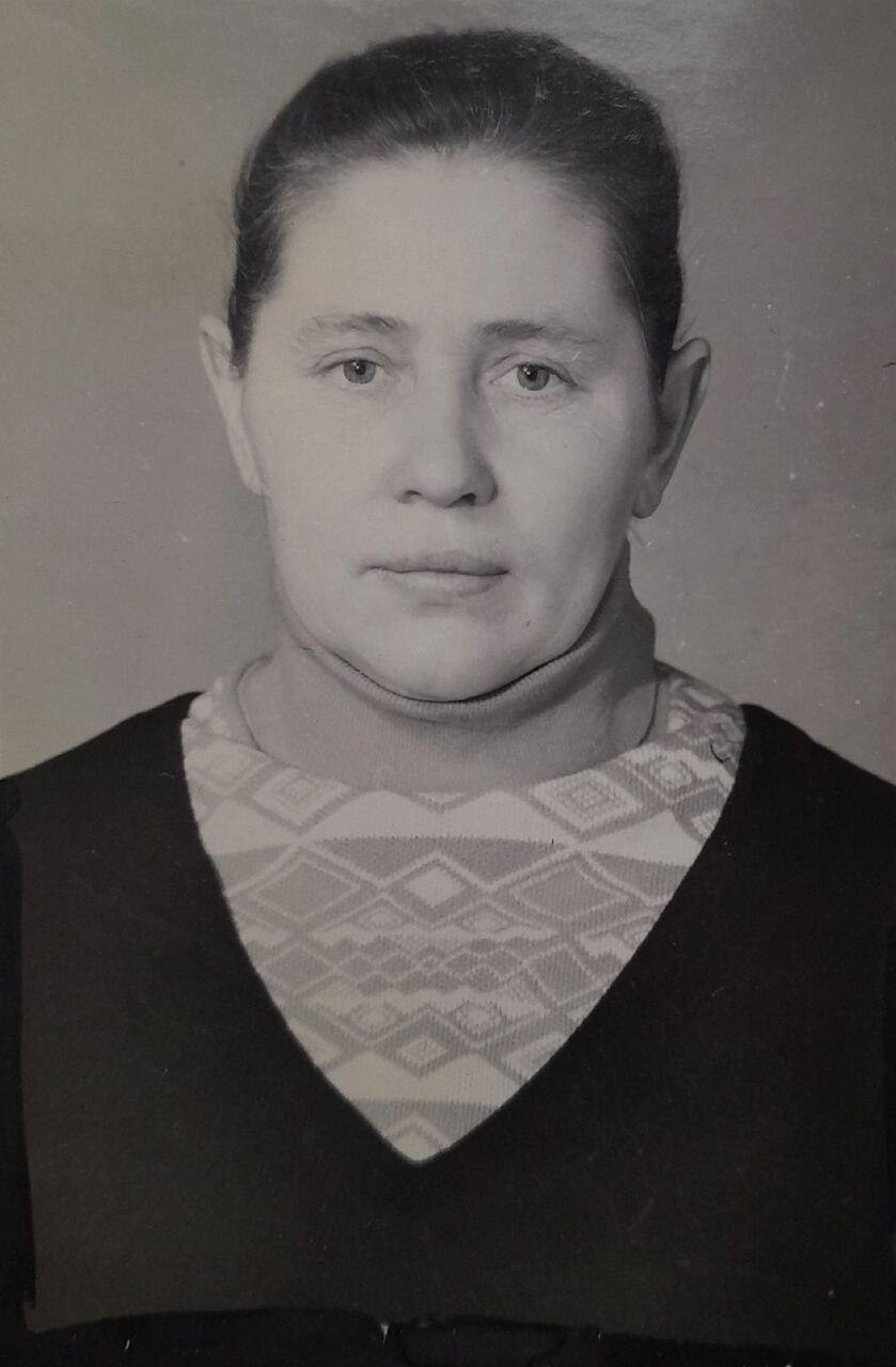 Чёрно-белая фотография: женщина с гладко зачёсанными волосами, в тёмном платье со светлой вязаной вставкой с узором.